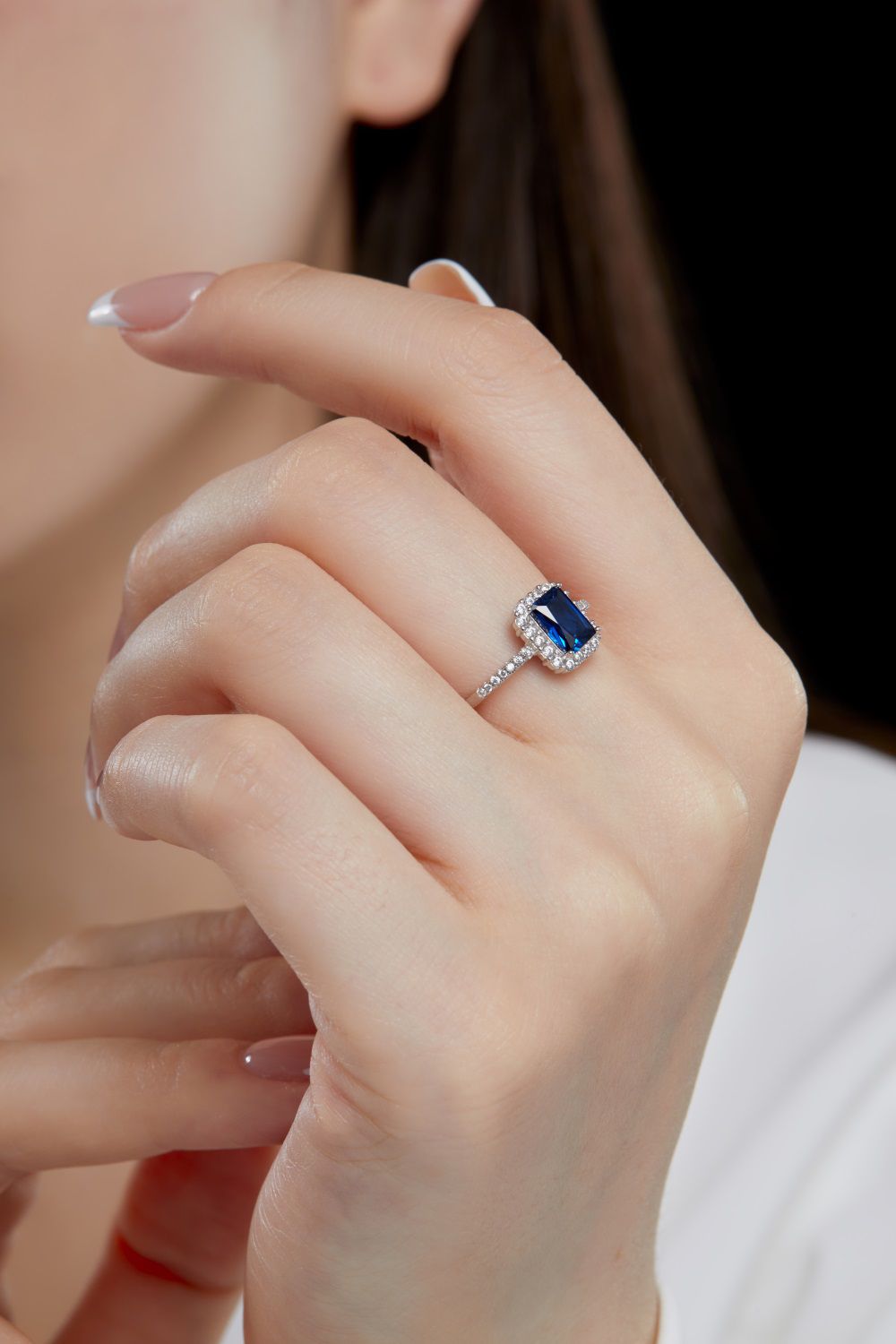 A rectangular-shaped royal blue sapphire ring with a metallic band and small clear stones set around it.