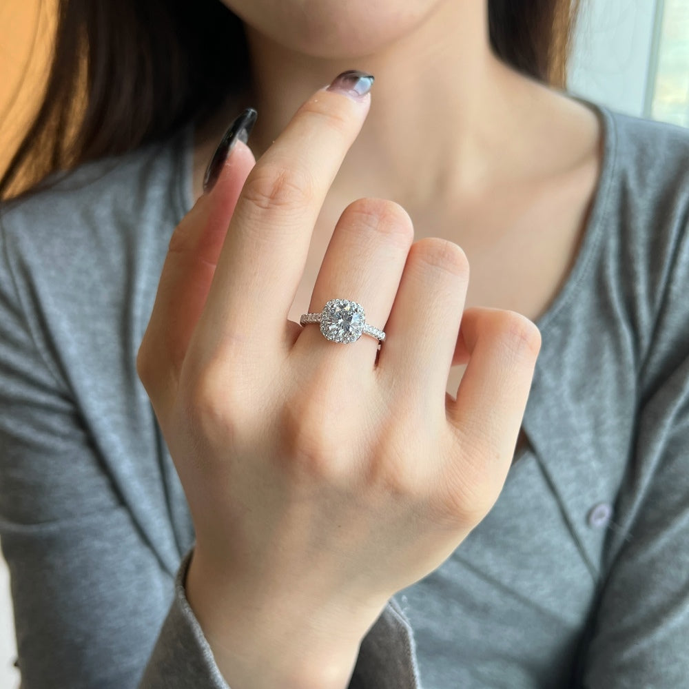 An elegant sterling silver ring featuring a round clear zircon stone with smaller clear stones around it, showcasing an inspired design presented on a hand.