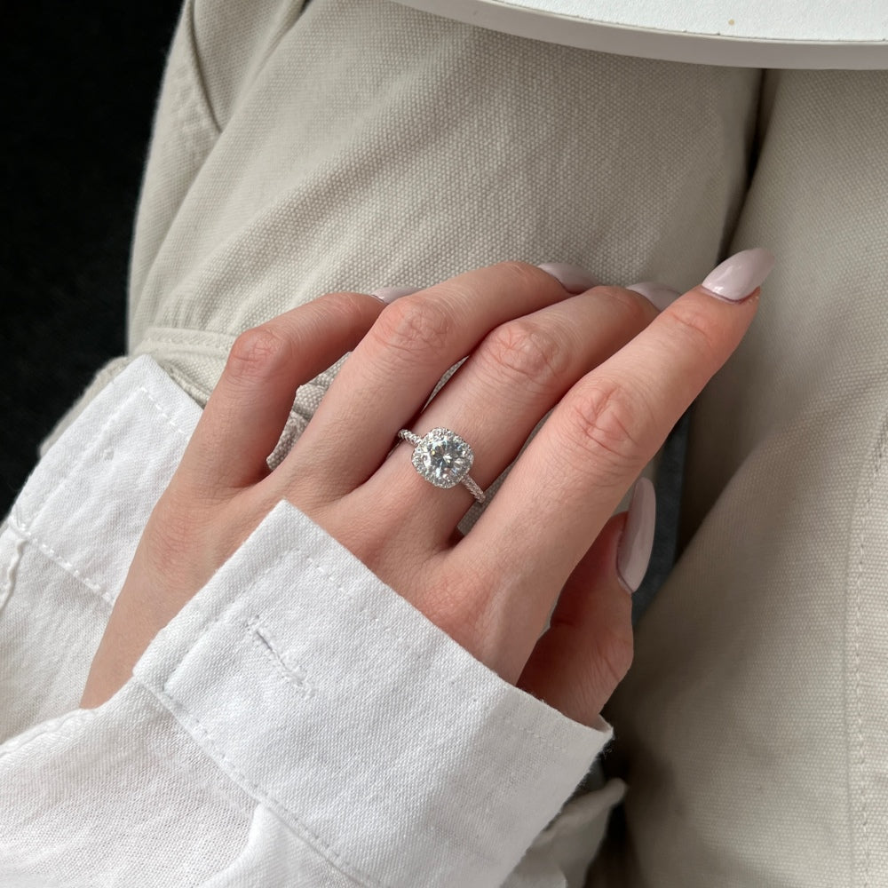 An elegant sterling silver ring featuring a round clear zircon stone with smaller clear stones around it, showcasing an inspired design.