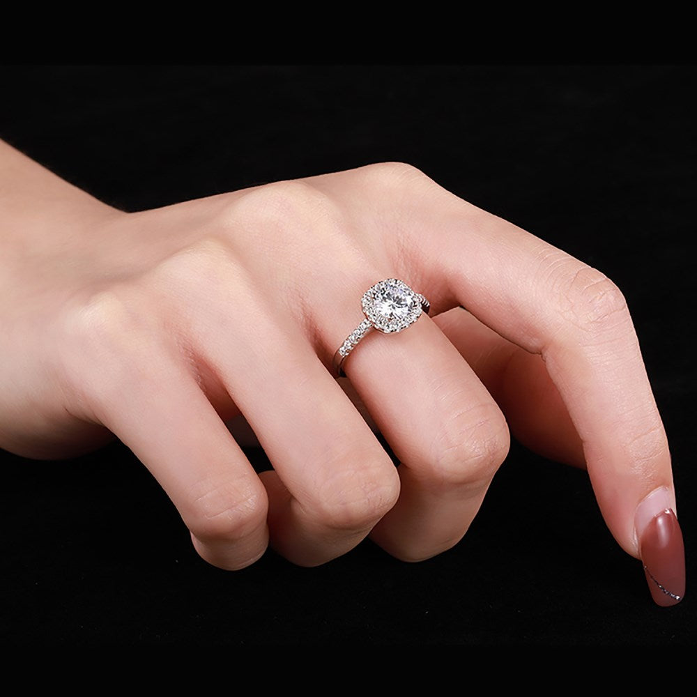 An elegant sterling silver ring featuring a round clear zircon stone with smaller clear stones around it, showcasing an inspired design.