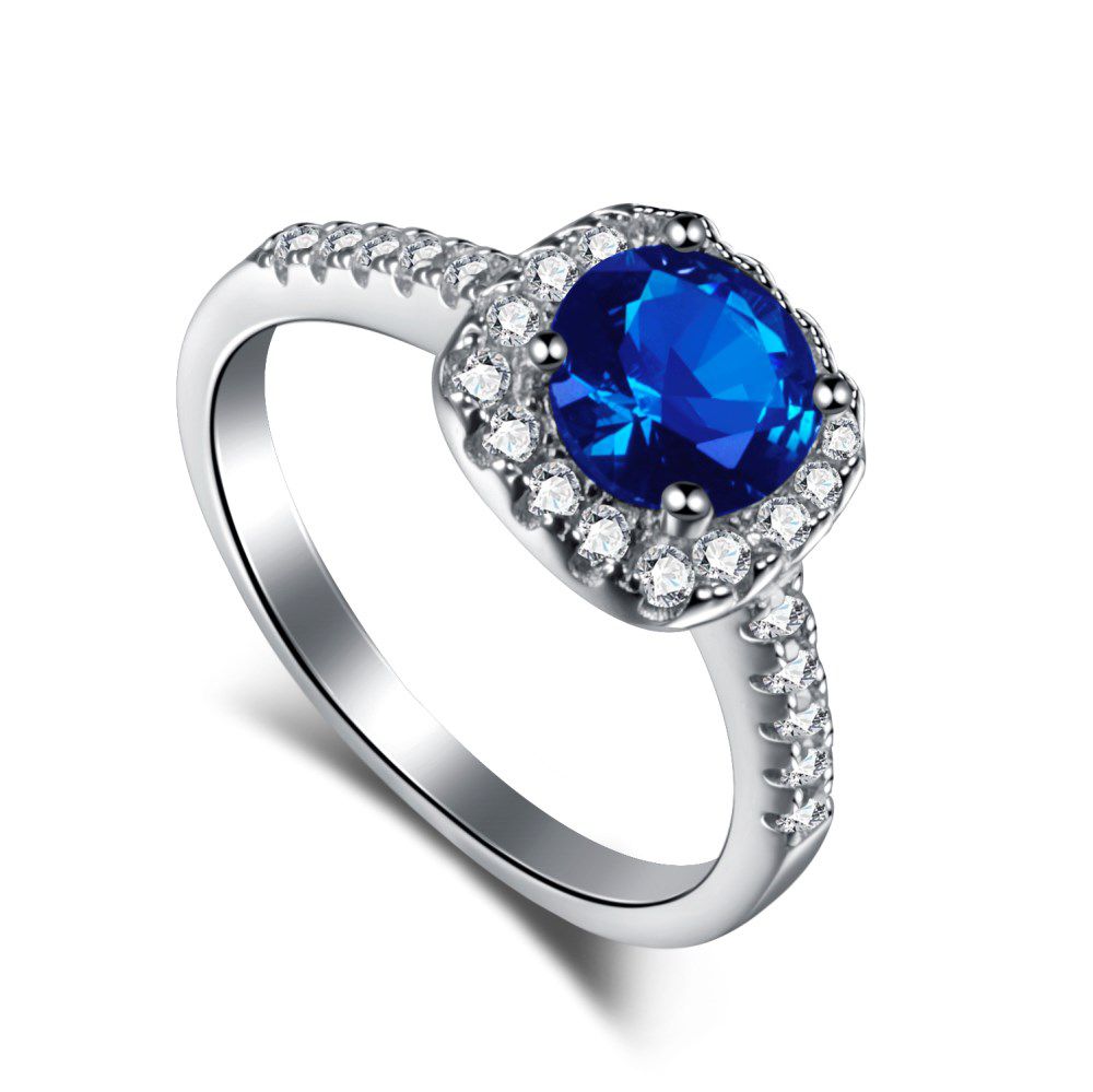 An elegant sterling silver ring featuring a round blue zircon stone with smaller clear stones around it, showcasing an inspired design.