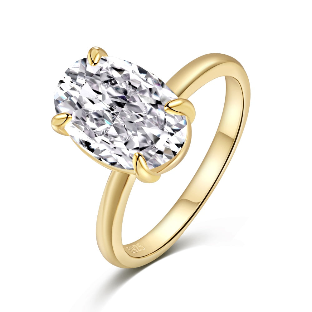 A gold-colored band solitaire ring with a large oval-shaped clear stone
