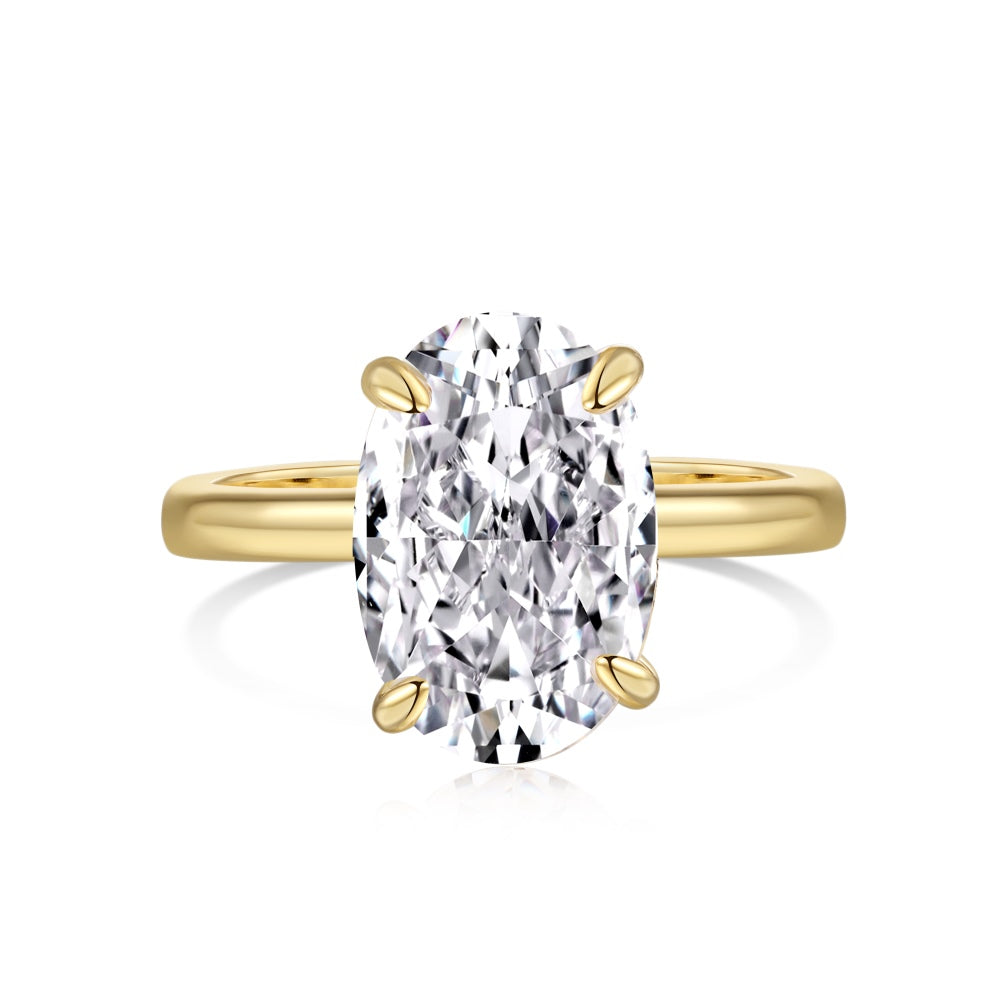 A gold-colored band solitaire ring with a large oval-shaped clear stone
