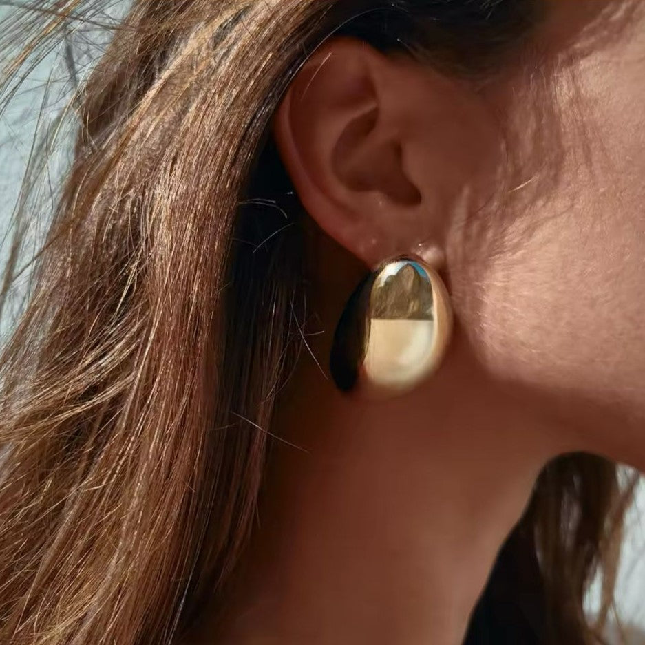 A gold glossy earring on a women's ear