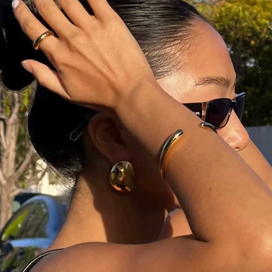 A gold glossy earring on a women's ear
