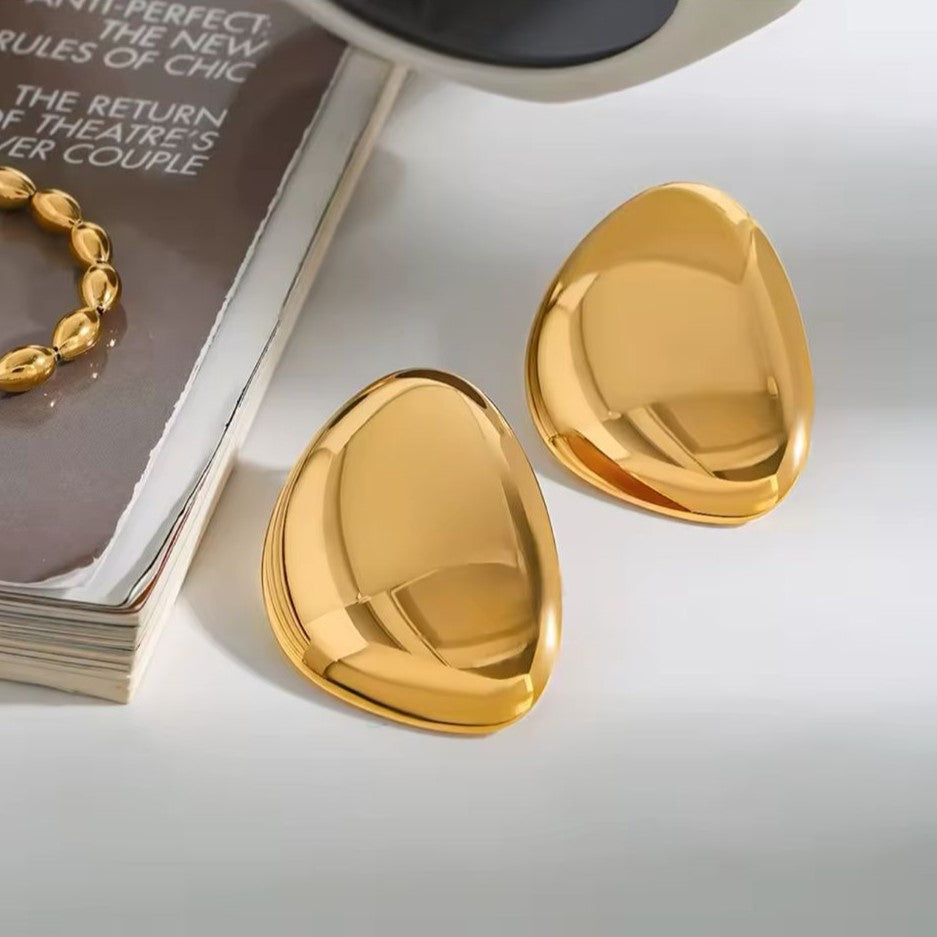 Pair of gold earrings on a white table background