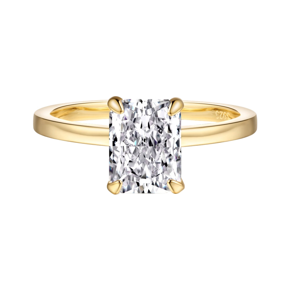 A gold band ring with a single rectangle-shaped clear stone set in a metallic setting.