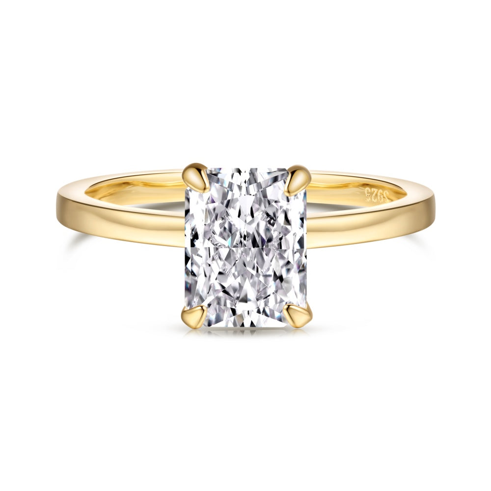 A gold band ring with a single rectangle-shaped clear stone set in a metallic setting.