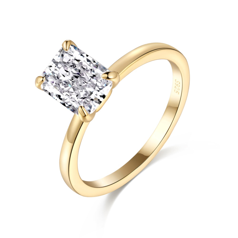 A gold band ring with a single rectangle-shaped clear stone set in a metallic setting.