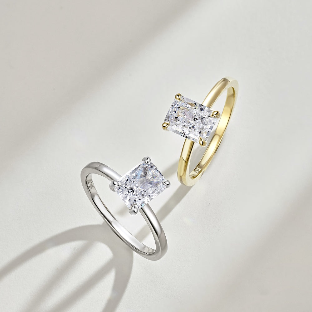 A gold & silver band ring with a single rectangle-shaped clear stone set in a metallic setting.