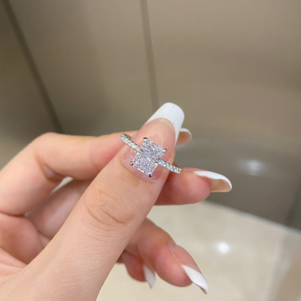 A rectangular radiant cut central diamond with smaller stones set in a silver band