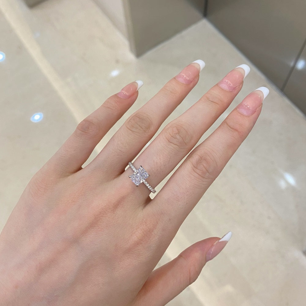 A rectangular radiant cut central diamond with smaller stones set in a silver band