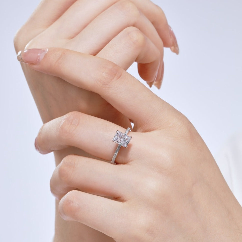 A rectangular radiant cut central diamond with smaller stones set in a silver band