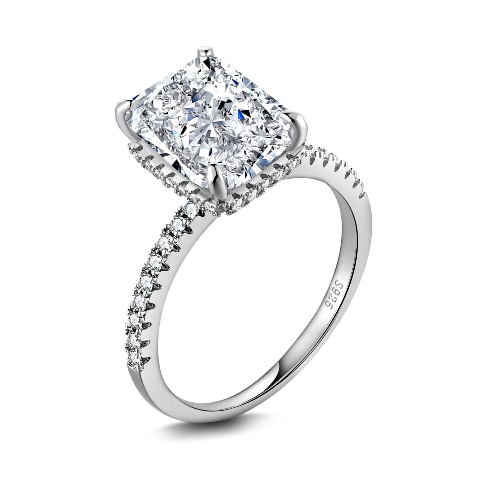 A silver-colored band engagement ring featuring a large rectangle-shaped central stone with smaller stones around it