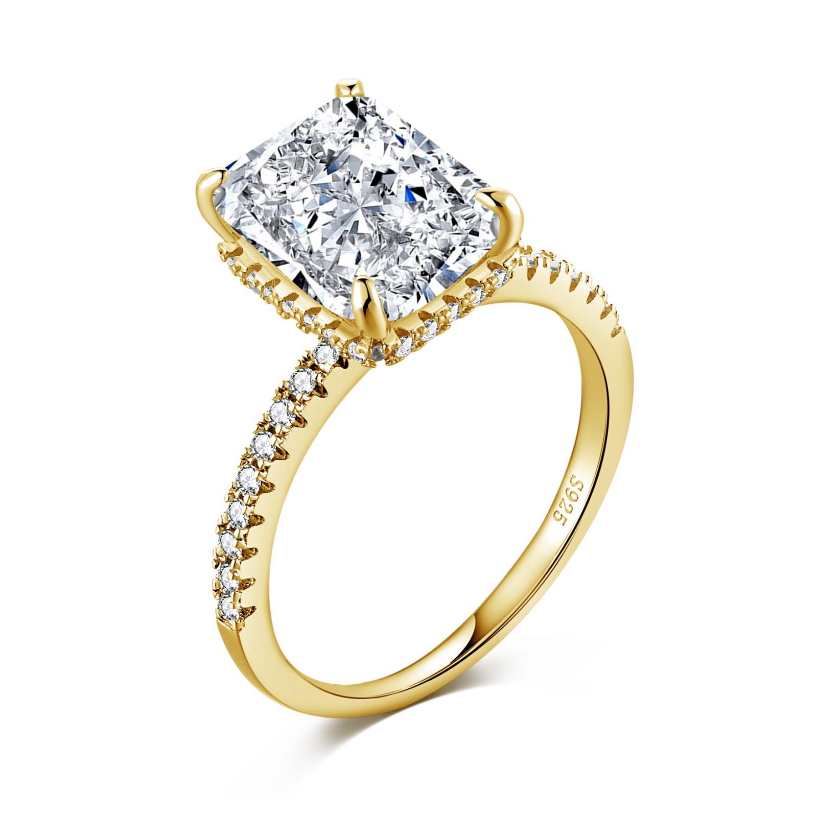 A gold-colored band engagement ring featuring a large rectangle-shaped central stone with smaller stones around it