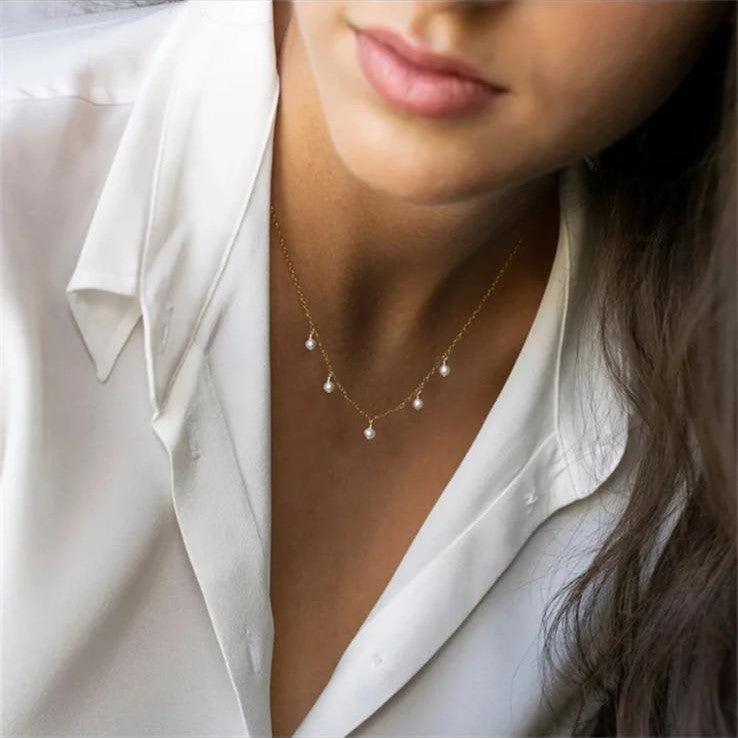 A gold-colored stainless steel necklace with five imitation pearl bead drops.