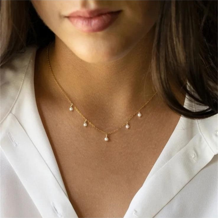 A gold-colored stainless steel necklace with five imitation pearl bead drops.