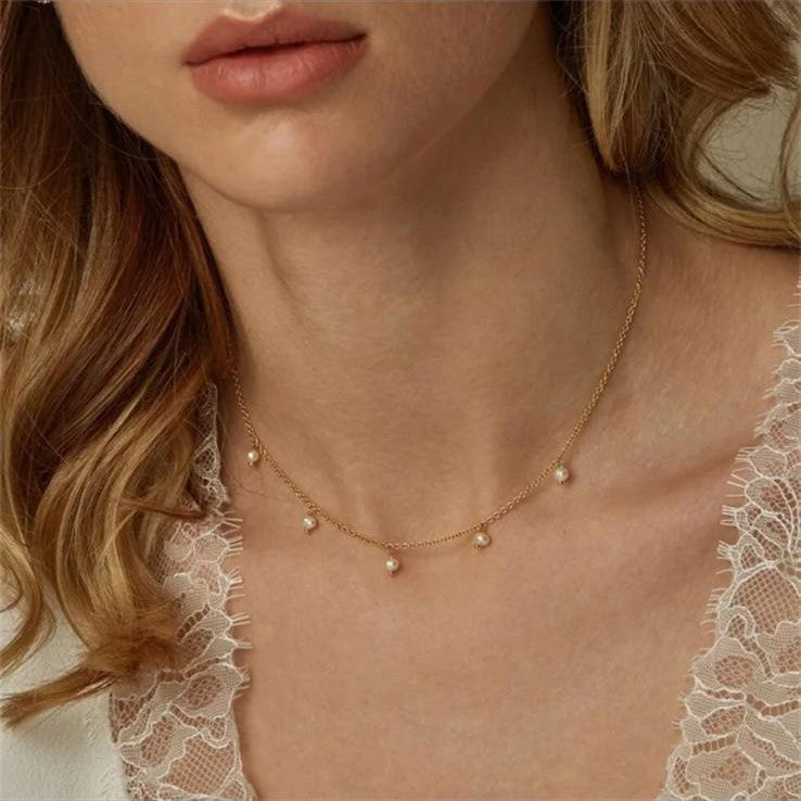 A gold-colored stainless steel necklace with five imitation pearl bead drops.