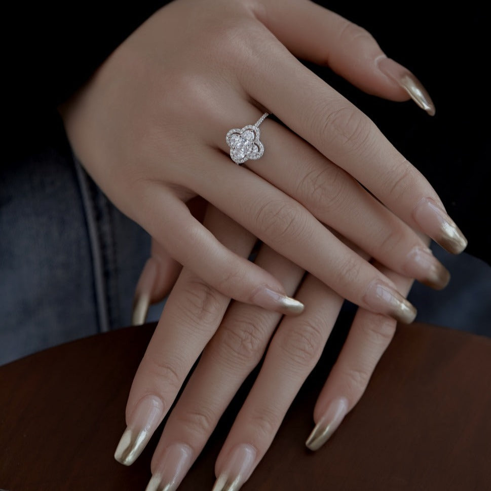A silver clover-shaped ring with multiple clear gemstones and a rhodium plating.