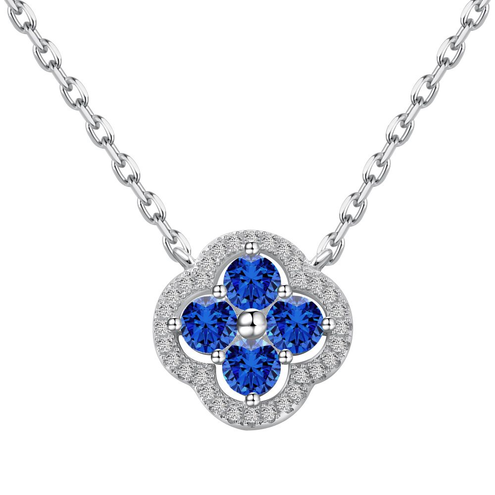 A silver necklace with a clover-shaped pendant adorned with blue cubic zirconia stones.