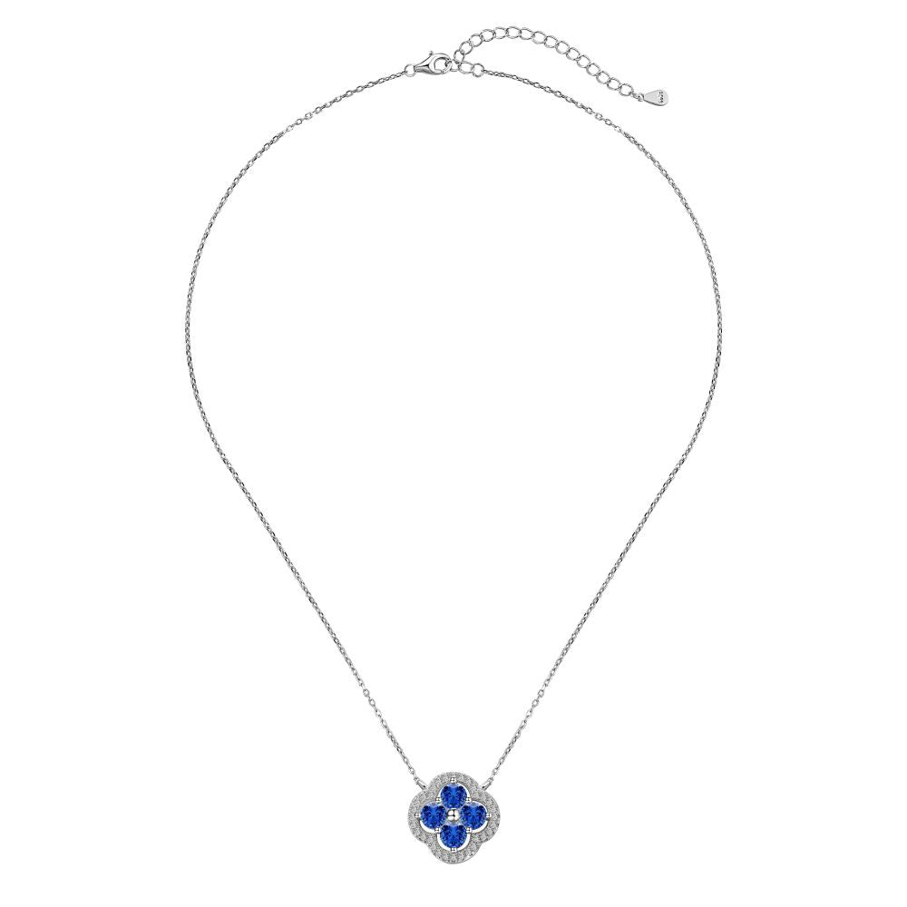 A silver necklace with a clover-shaped pendant adorned with blue cubic zirconia stones.