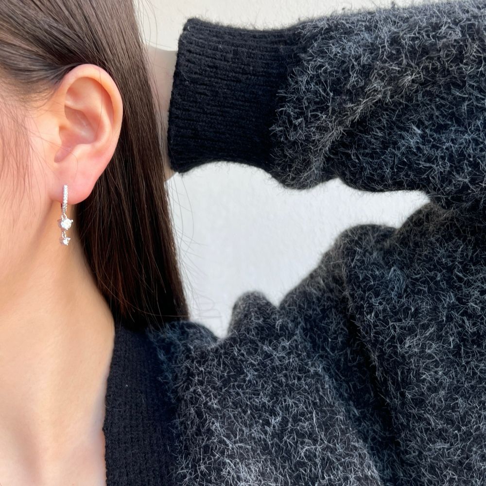 A silver gold-plated hoop earring with drop-shaped setting containing cubic zirconia stone.