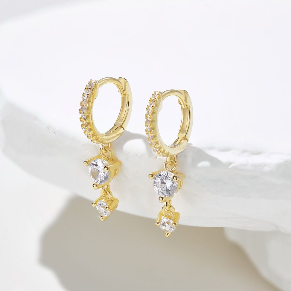 A pair of gold-plated hoop earrings with drop-shaped settings containing cubic zirconia stones.