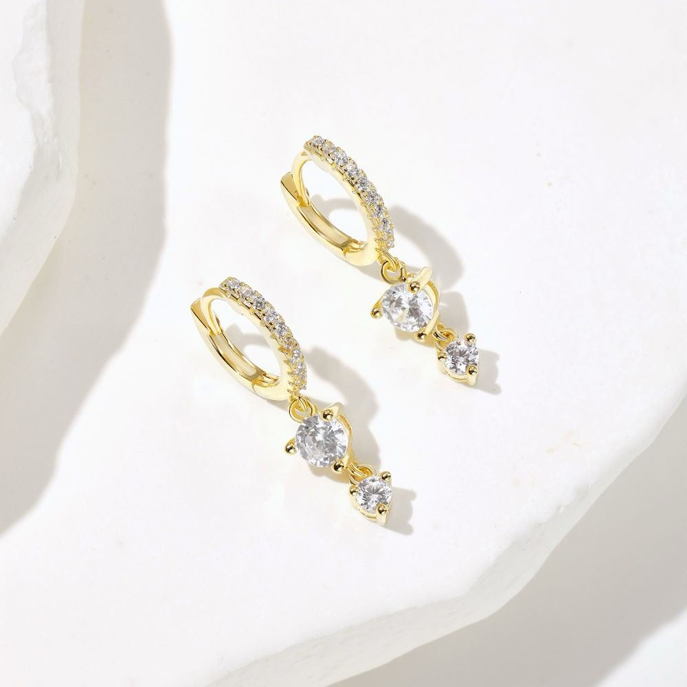 A pair of gold-plated hoop earrings with drop-shaped settings containing cubic zirconia stones.
