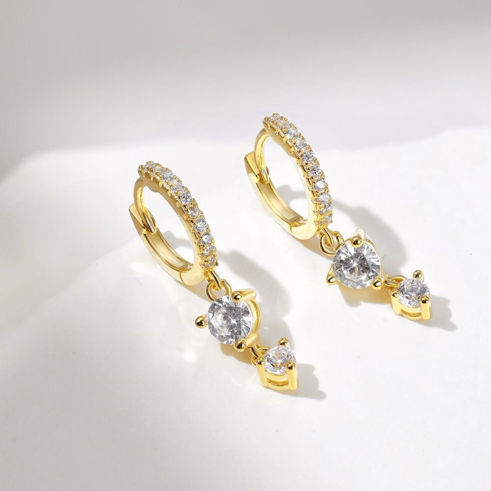 A pair of gold-plated hoop earrings with drop-shaped settings containing cubic zirconia stones.