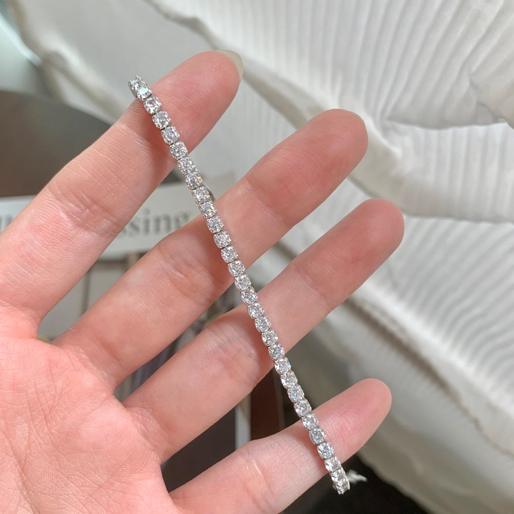 A sterling silver tennis bracelet with silver accents and cubic zirconia stones.