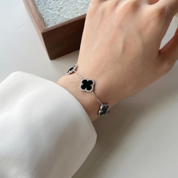 An elegant 925 sterling silver bracelet featuring a clover design with black shell accents with an adjustable chain.