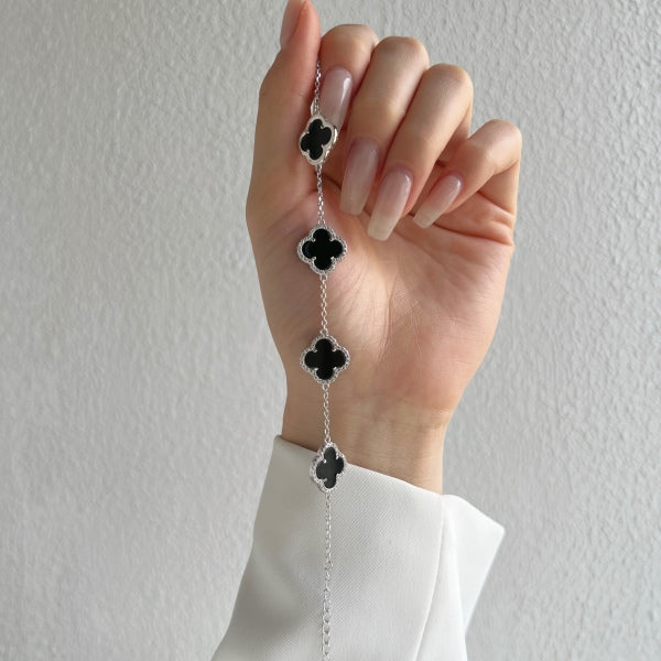 An elegant 925 sterling silver bracelet featuring a clover design with black shell accents with an adjustable chain.