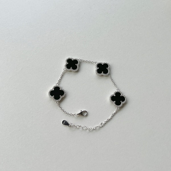 An elegant 925 sterling silver bracelet featuring a clover design with black shell accents with an adjustable chain.