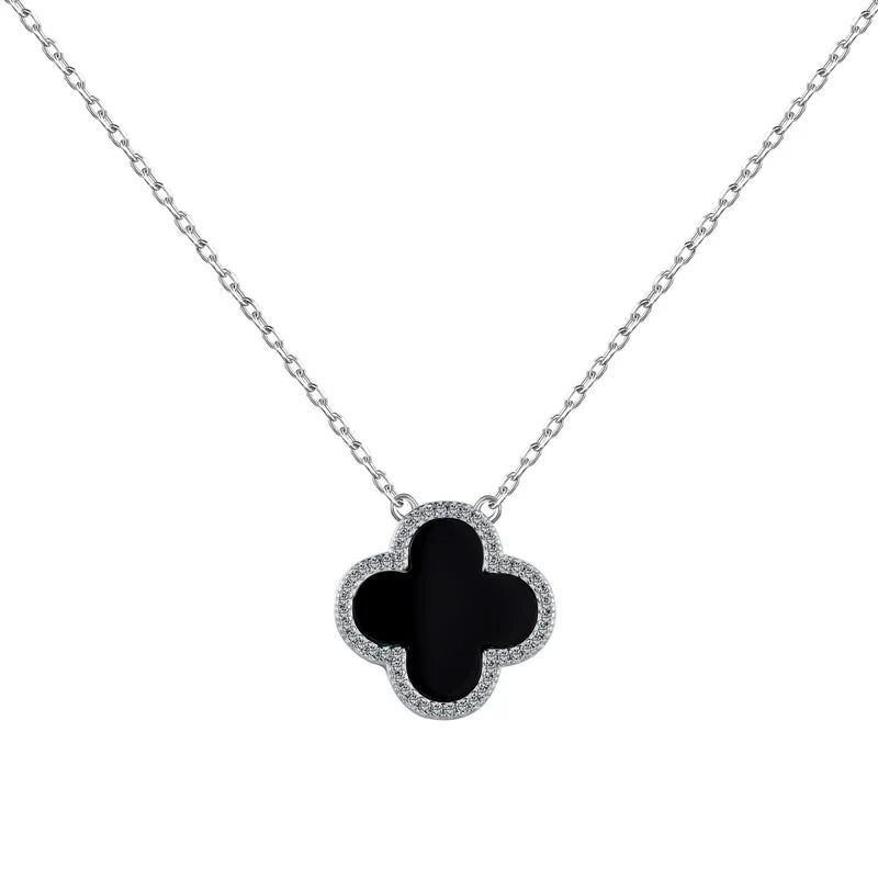 A silver necklace featuring a clover design with black shell accents on a chain.