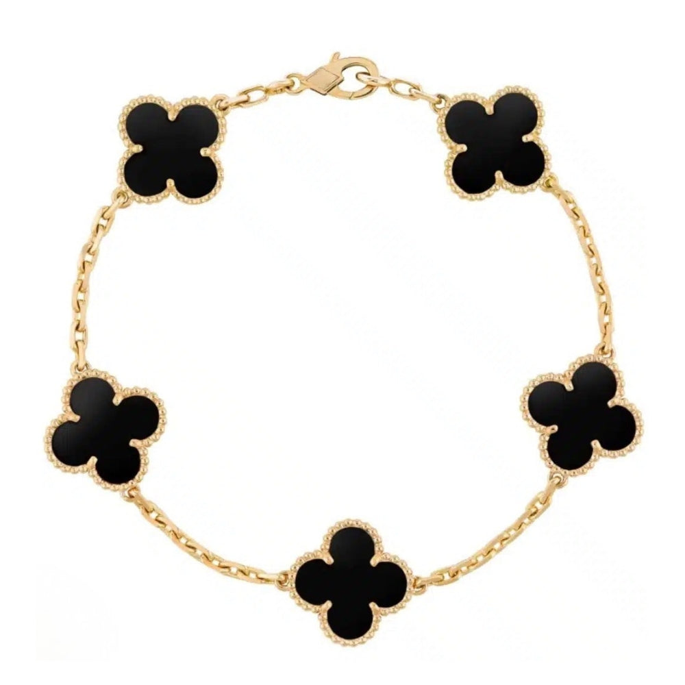 Gold bracelet with black clover-shaped links on a white background