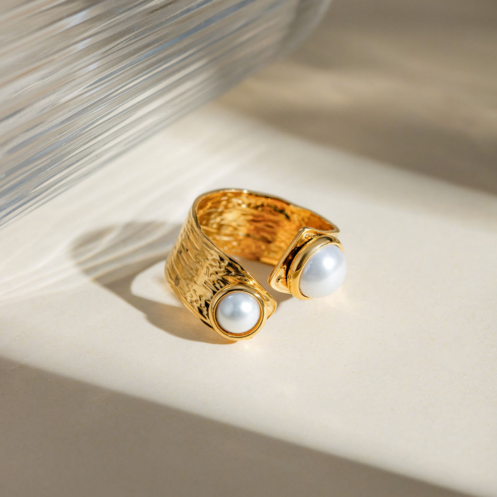 Gold ring with two pearls on a light background