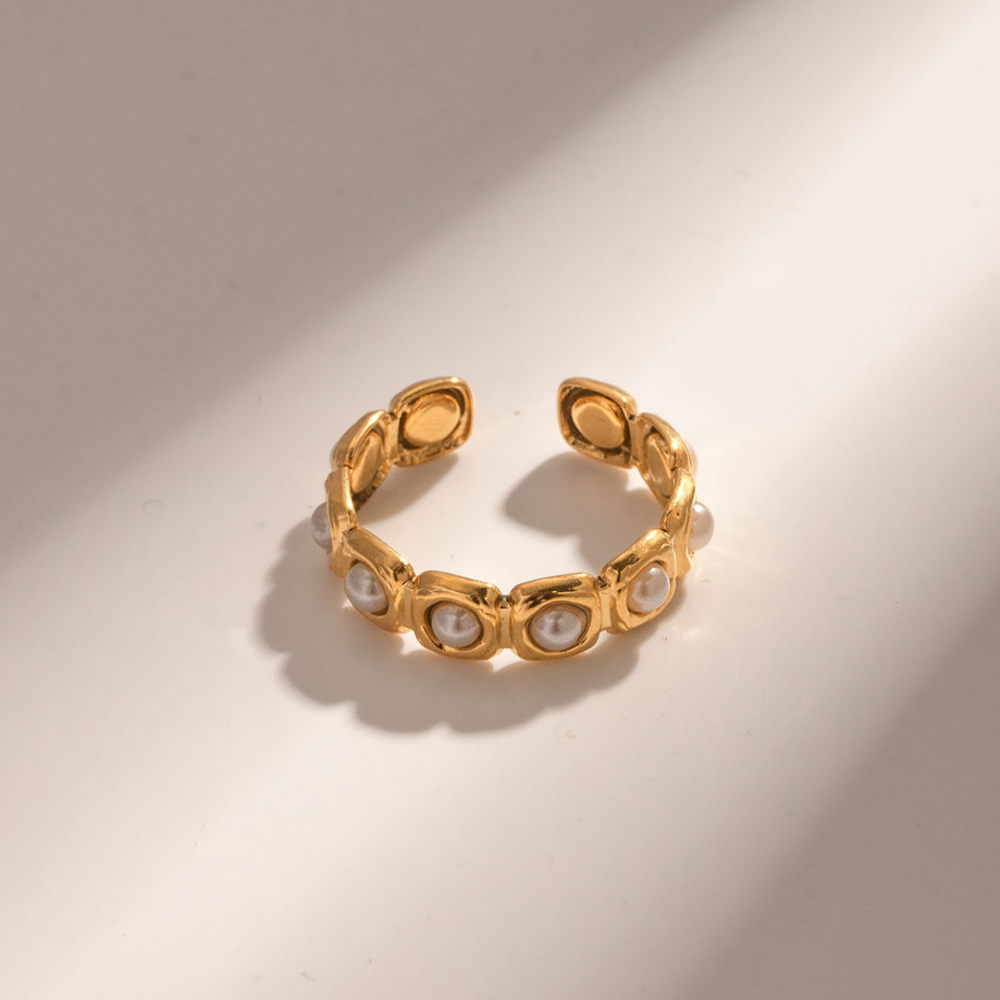Gold ring with pearl-like stones on a beige background