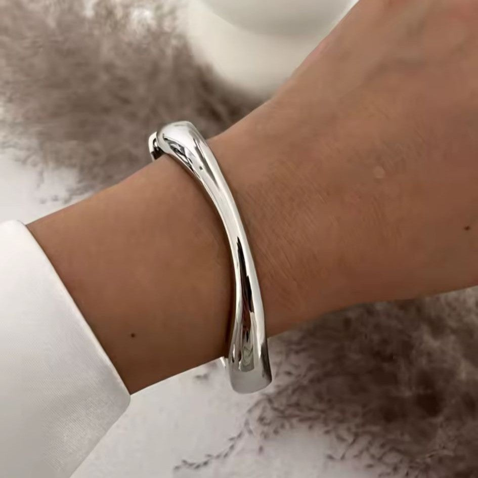 Silver bracelet on a wrist with a neutral background