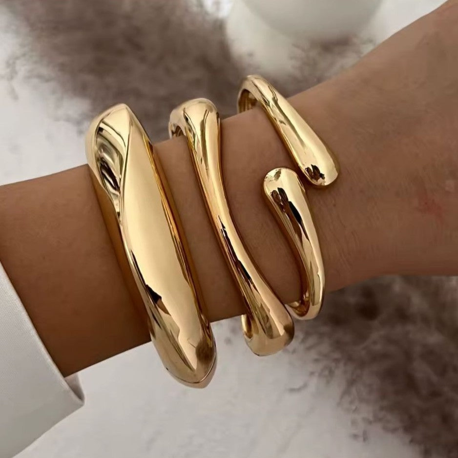Gold bracelet on a wrist with a neutral background