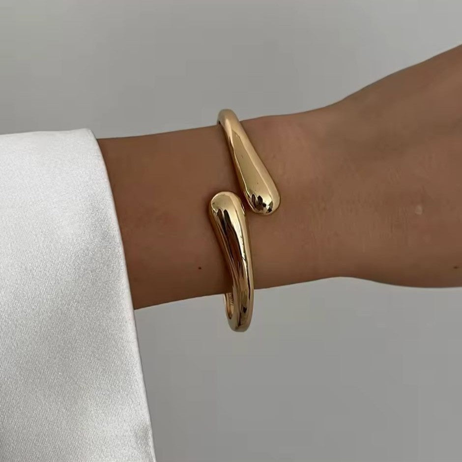 Gold bangle on a wrist with a neutral background