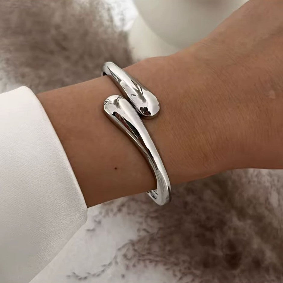 Silver bracelet on a wrist with a neutral background