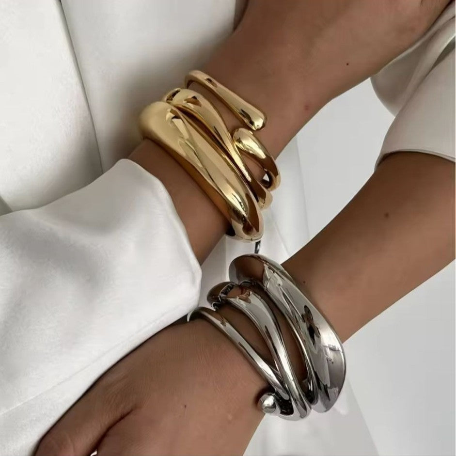 Gold and silver bracelets on a person's wrist against a white background