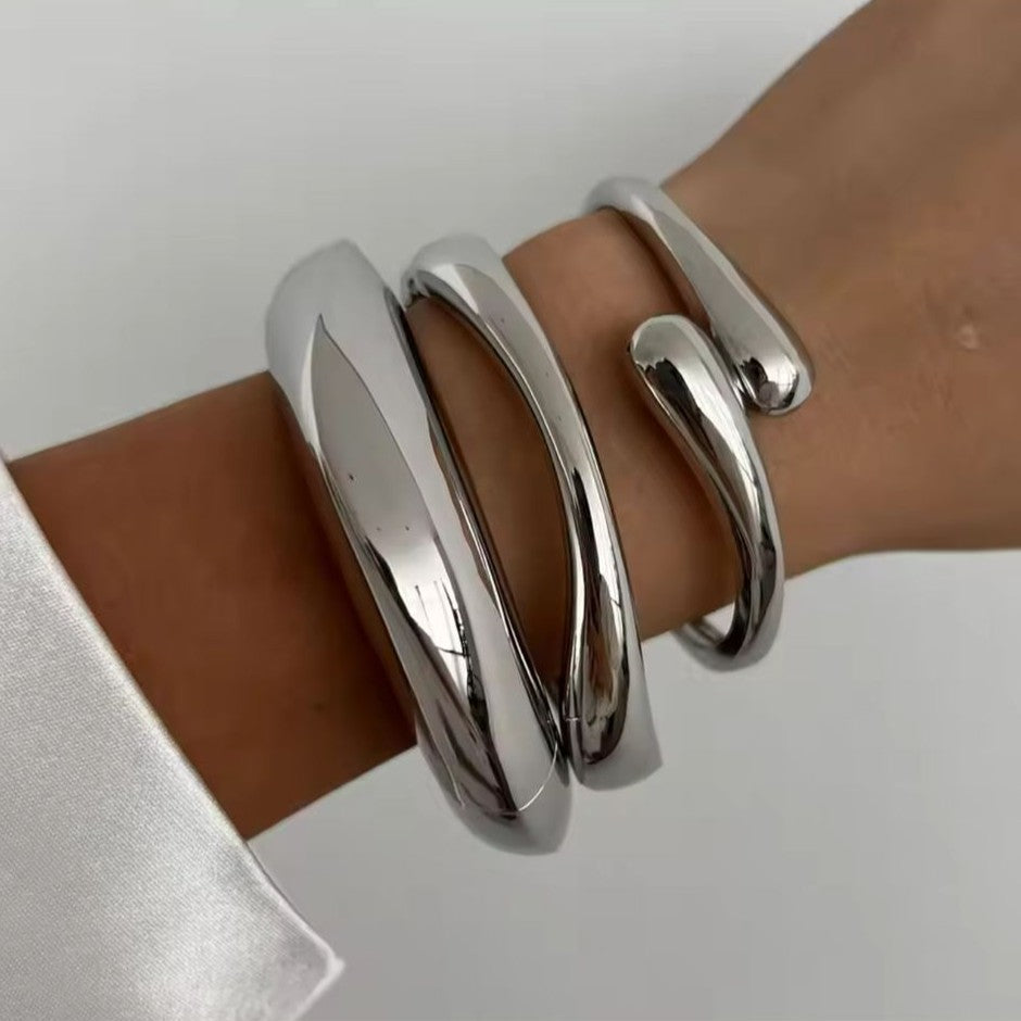 Silver bracelet on a wrist against a neutral background
