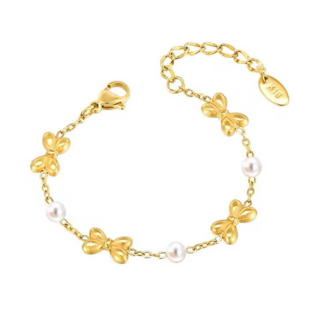 Gold bracelet with bow-shaped charms and pearls on a white background