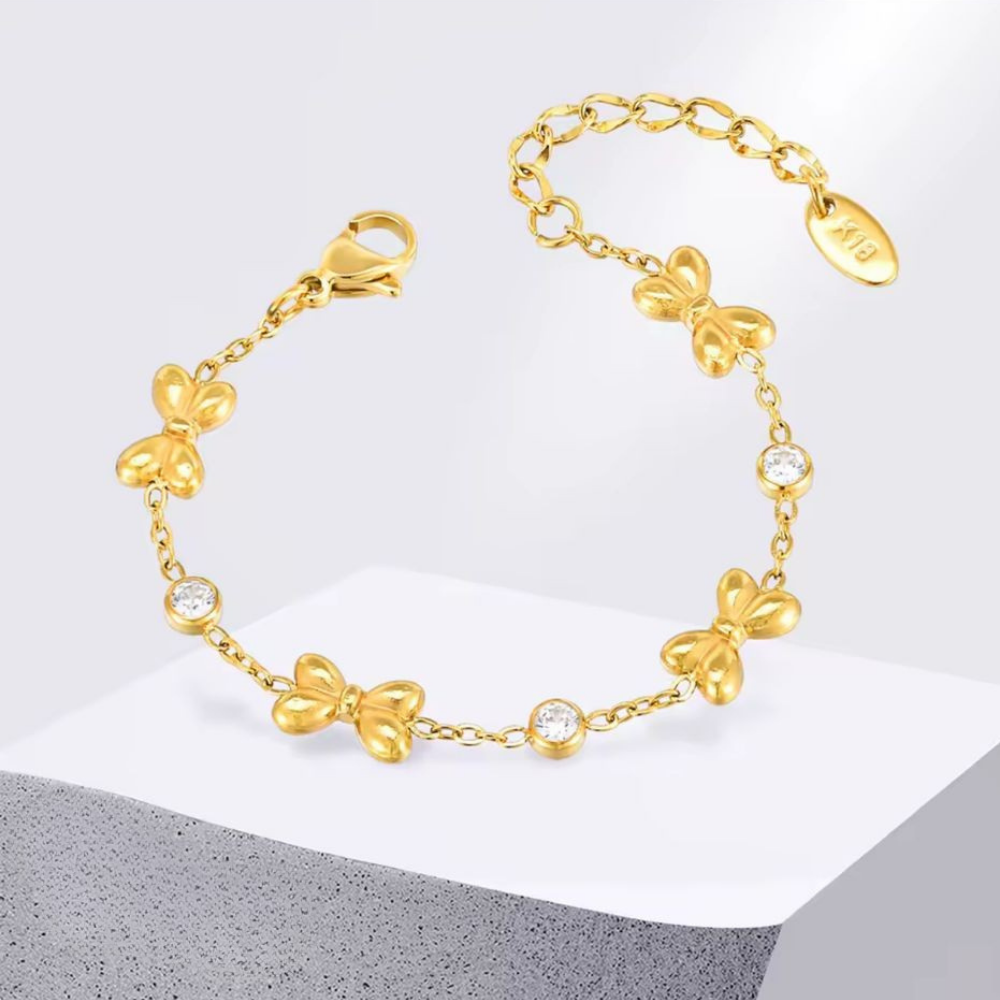 Gold bracelet with butterfly designs on a light gray background