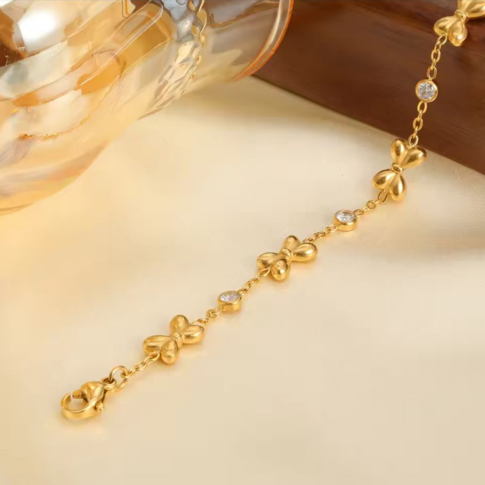 Gold bracelet with bow-shaped links on a beige background