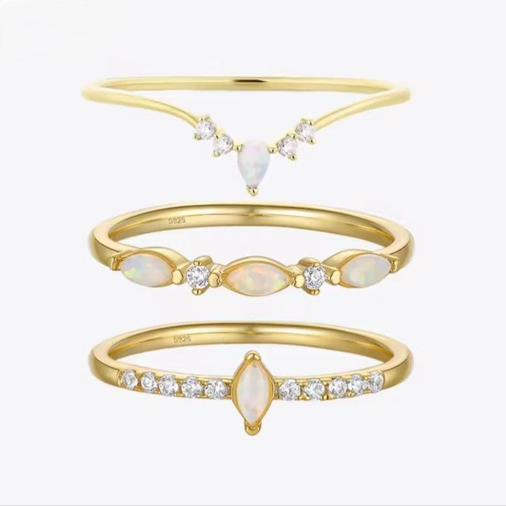 Set of three celestial gold rings with opal and diamond accents on a white background.