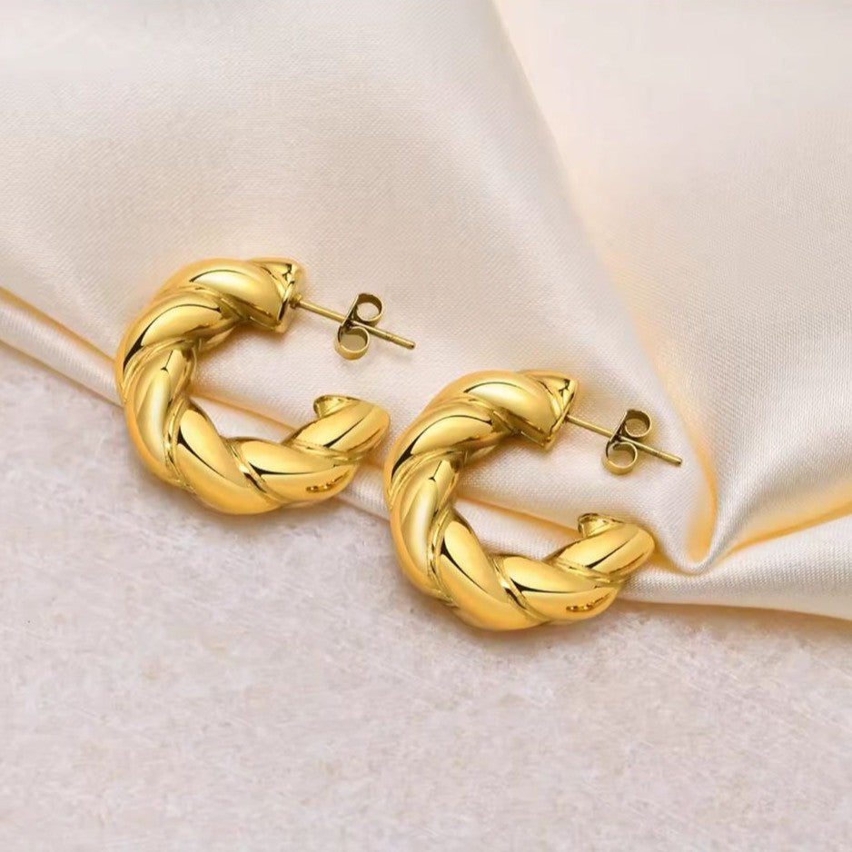 Gold hoop earrings on a soft beige fabric background