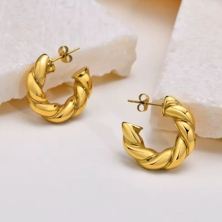 Gold hoop earrings on a soft white background