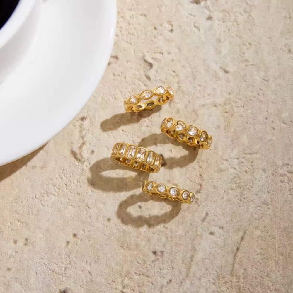 Gold rings with embedded stones on a textured beige surface